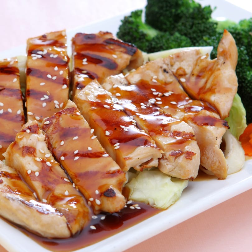 Grilled chicken slices with teriyaki sauce and sesame seeds, served with broccoli and cabbage.